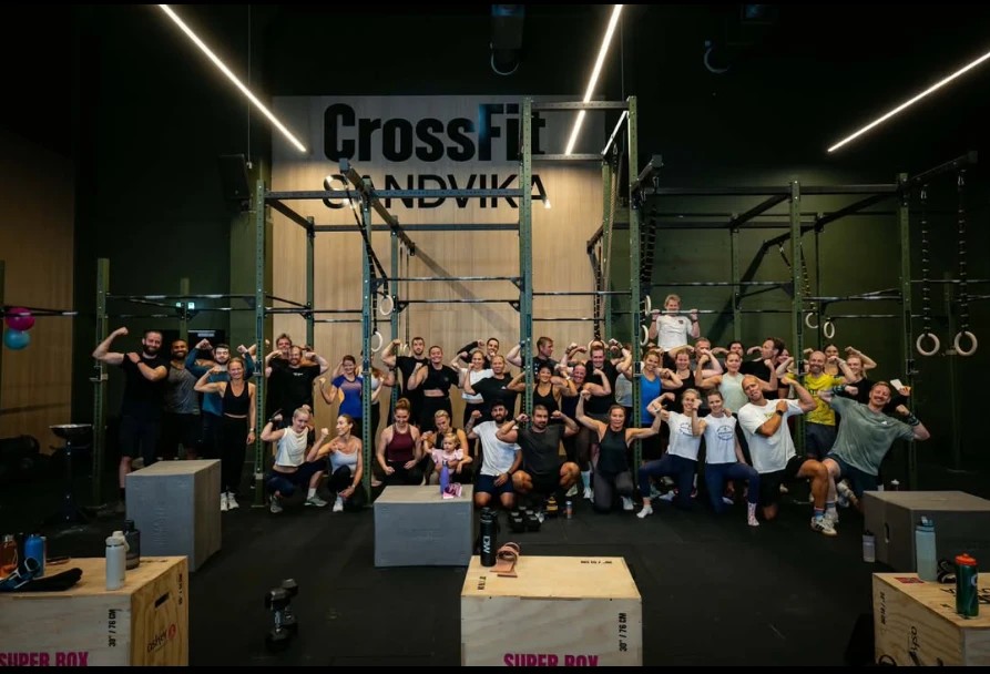 Medlemmer og coacher samlet foran CrossFit Sandvika-logoen